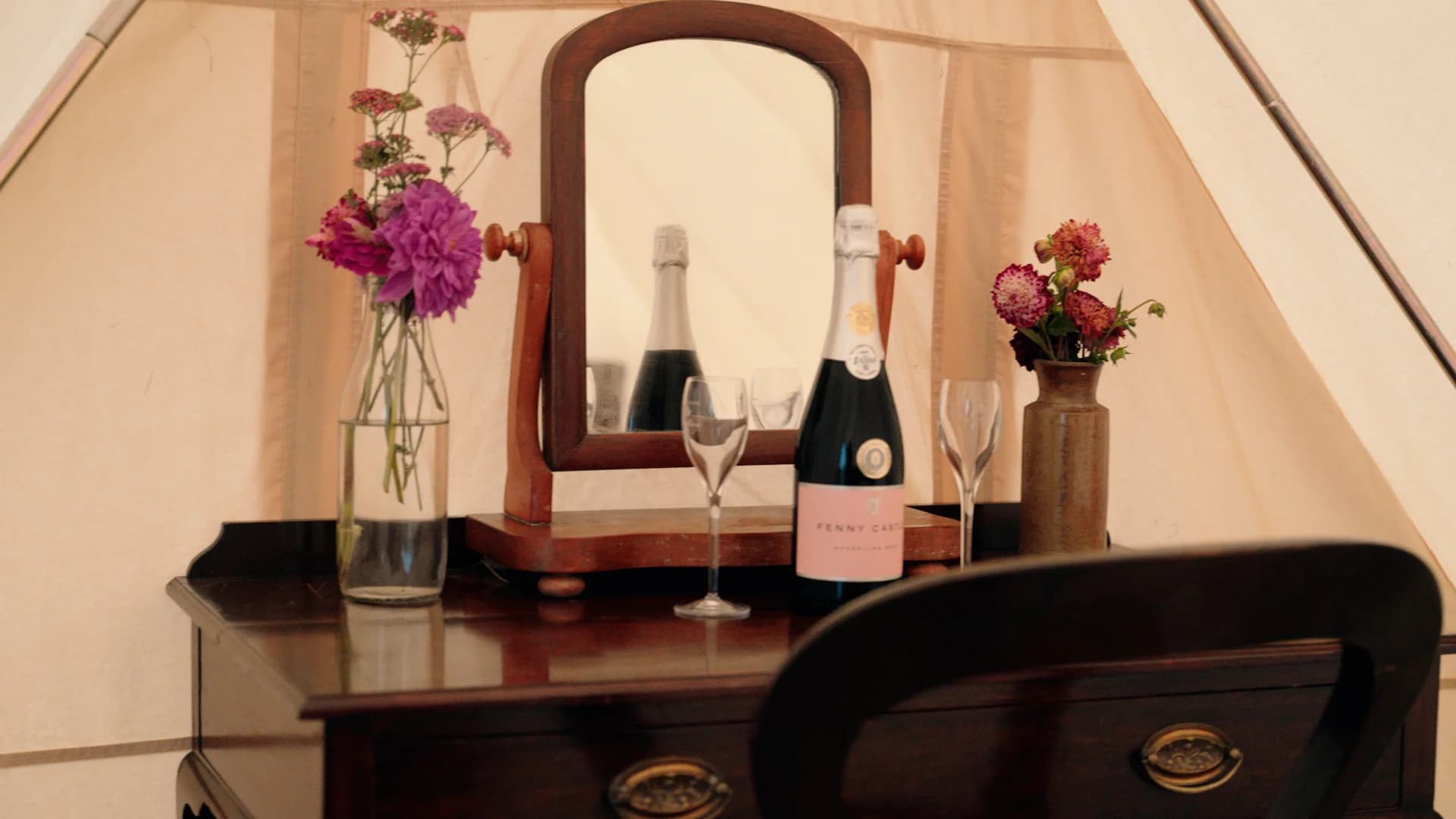 Champagne and flowers arranged on a dressing table with a mirror, inside a Hotel Melody Rhythm Resort tent.